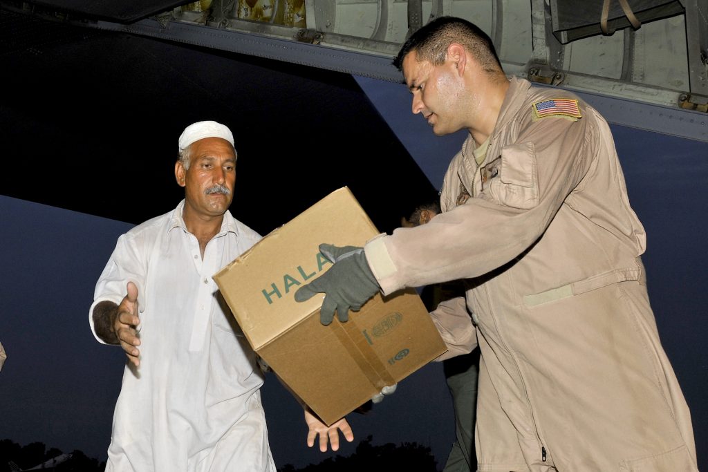 Senior Airman Jose Cornejo, a loadmaster assigned to the 455th Air Expeditionary Wing, hands boxes of Halal meals to Pakistanis after arriving at Peshawar, Pakistan, Aug. 1, 2010. The U.S. Air Force flew thousands of meals to Pakistan as part of a humanitarian relief mission to help flood victims. Airman Cornejo is a native of Chicago, Ill.