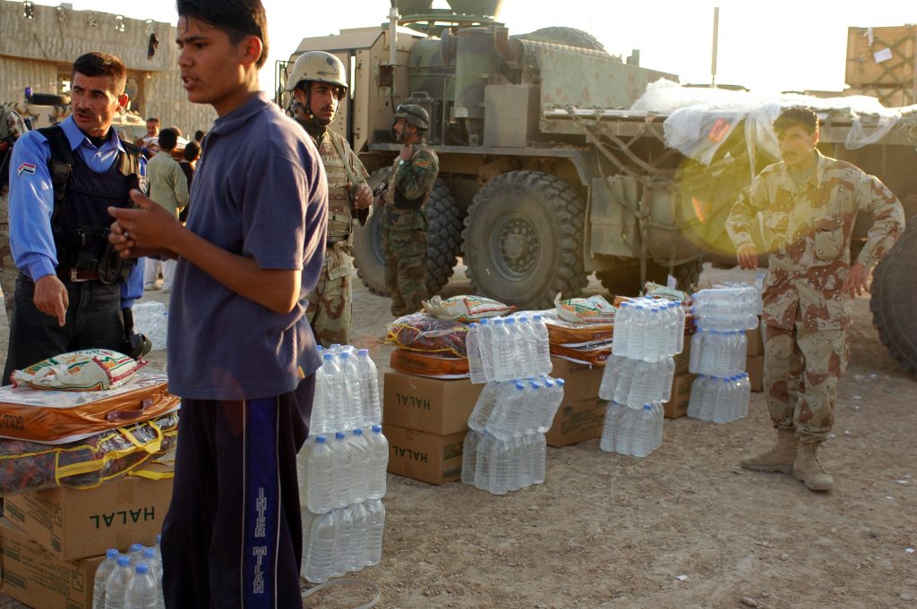 Iraqi security forces assists a young man gather aide for the survivors of a recent bomb attack in Tal Afar. During the relief effort, the Iraqi army and Coalition Forces distributed 500 blankets, 6,500 Halal meals, 16 pallets of water, and 200 bags of rice for the local Iraqi citizens in Tal Afar to provide humanitarian assistance after the March 29, 2007 insurgent attacks. (Staff Sgt. Samantha M. Stryker)(Released)