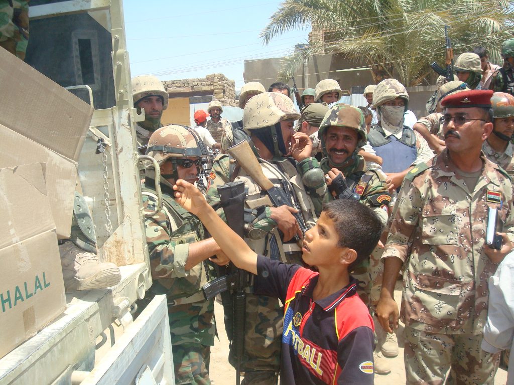 An Amarah boy reaches out for a Halal meal, as Iraqi army soldiers look on June 22. The IA-led humanitarian assistance mission was a huge success, said Col. Ali Ayid, 10th IA Division civil affairs officer. IA soldiers handed out 8,316 meals to 12 different neighborhoods in Amarah. We had a large turnout and all of the citizens looked extremely grateful for assistance, said Ayid.