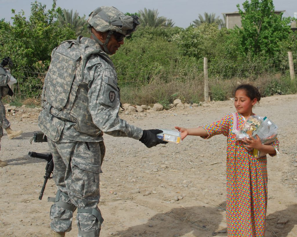 Command Sgt. Maj. Thomas Jones Jr., command sergeant major, Headquarters and Headquarters Company, 2nd Battalion, 35th Infantry Regiment, 25th Infantry Division, hands a Halal meal to a young Iraqi girl in Bara'ia, Samarra, Iraq.